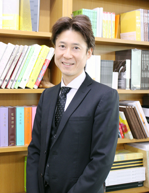 クータ・バインディングで製本された書籍の前で渋谷社長 クータ・バインディングで製本された書籍の前で渋谷社長